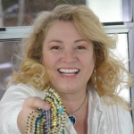 Person with long slightly wavy blond hair holding out a fistful of mardi gras beads